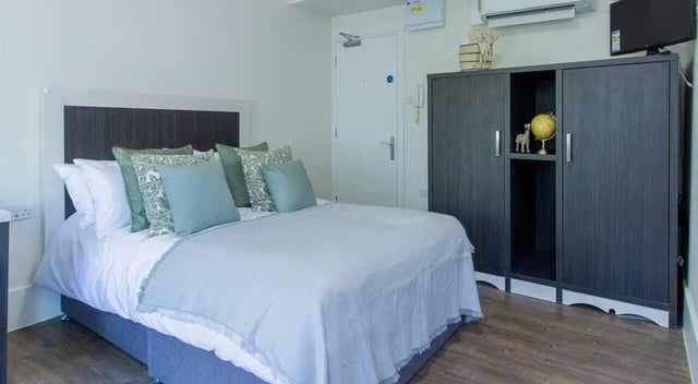 Bed pillows wardrobe globe and TV bedroom at Bloomsbury Janet Poole House in London Student Accommodation