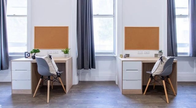 Two desks chairs corkboards window study area at Bloomsbury Janet Poole House in London Student Accommodation