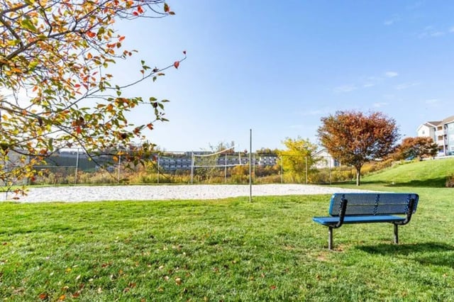 Blue bench on grass near volleyball court exterior at West Run in Morgantown Student Accommodation