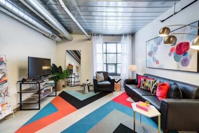 Black leather sofa colorful pillows geometric rug living room at The Abigail in Columbus Student Accommodation