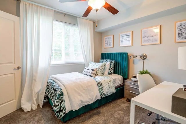 Bed with teal headboard desk chair and window Bedroom at The Flats at Douglas in Toledo Student Accommodation