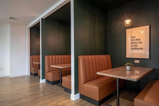 Orange booths with tables and artwork communal area at The Outpost Fort Collins in Fort Collins Student Accommodation
