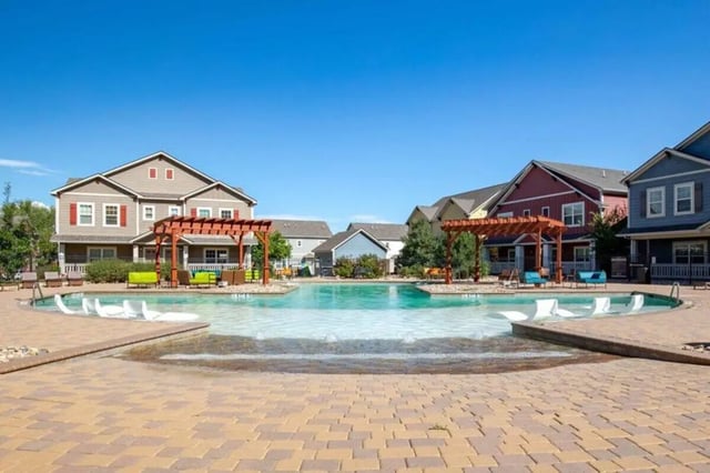 Swimming pool with lounge chairs and apartment buildings exterior at The Outpost Fort Collins in Fort Collins Student Accommodation
