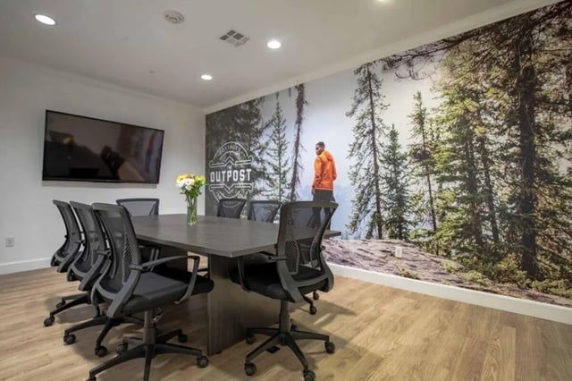 Conference table chairs wall mural with forest and person meeting room at The Outpost Fort Collins in Fort Collins Student Accommodation