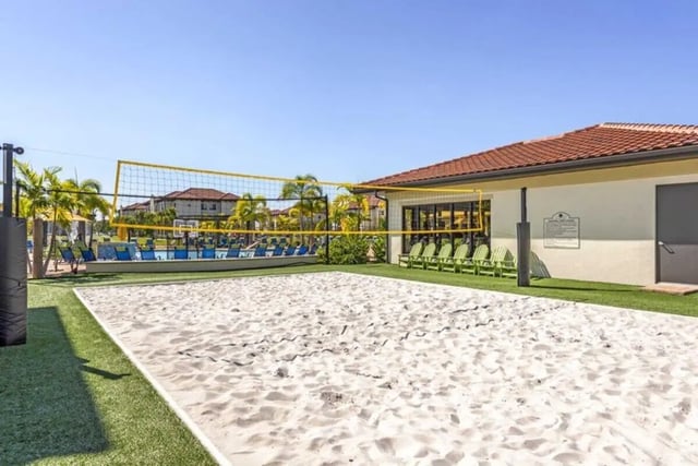 Volleyball court with chairs and pool exterior at The Reef in Fort Myers Student Accommodation