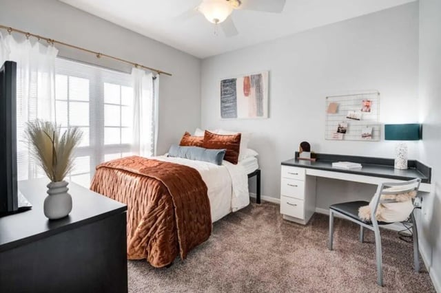 Bed desk ceiling fan white curtains bedroom at The Lodge on the Trail in West Lafayette Student Accommodation