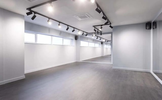 Empty room with mirrors track lighting ceiling speakers Studio at New Medlock House in Manchester Student Accommodation