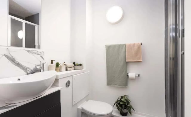 Sink toilet shower towels plant bathroom at New Medlock House in Manchester Student Accommodation
