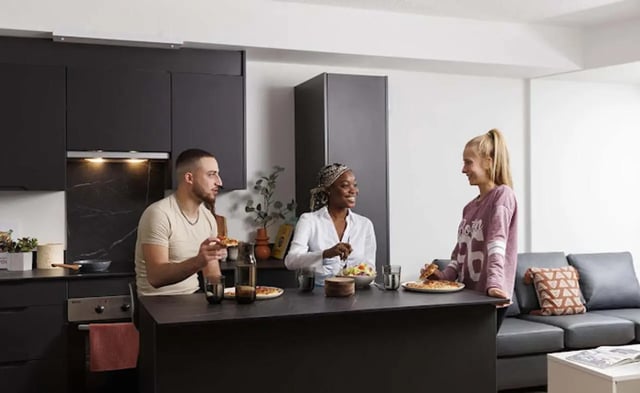 People eating pizza on kitchen island living room at New Medlock House in Manchester Student Accommodation