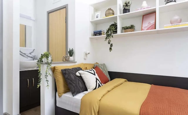 Bed with yellow and orange blankets and cushions bedroom at New Medlock House in Manchester Student Accommodation