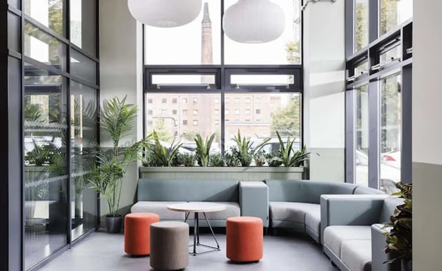 Lounge area with sectional sofa round table ottomans living room at New Medlock House in Manchester Student Accommodation