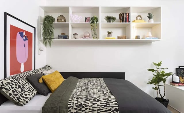 Bed with patterned pillows shelves and artwork bedroom at New Medlock House in Manchester Student Accommodation