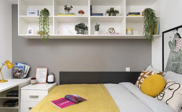 Bed with yellow blanket and decorative pillows bedroom at Parkway Gate in Manchester Student Accommodation