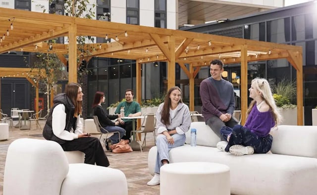 Students relaxing on white outdoor sofas patio area at Parkway Gate in Manchester Student Accommodation
