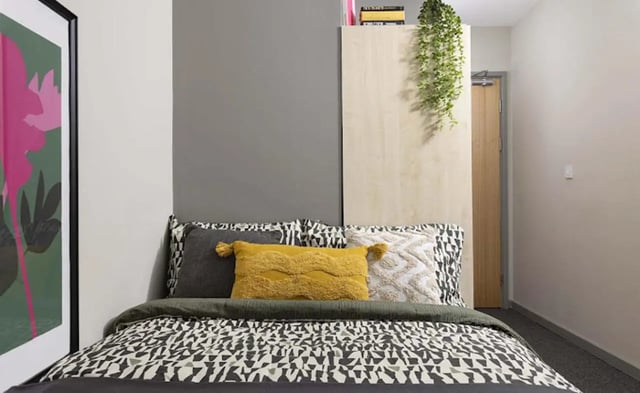 Bed with patterned duvet yellow pillow and artwork bedroom at Piccadilly Point in Manchester Student Accommodation