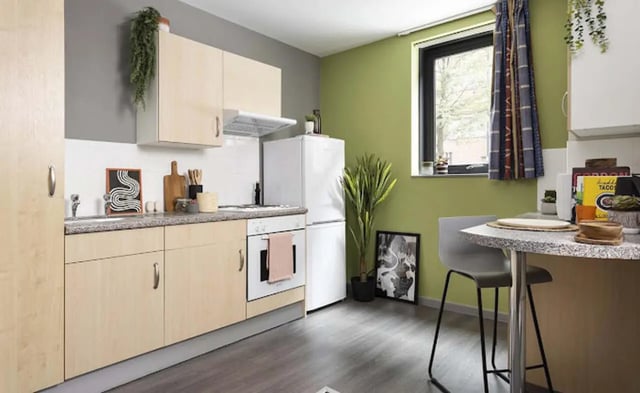Kitchen with light wood cabinets white fridge and dining area Kitchen at Piccadilly Point in Manchester Student Accommodation