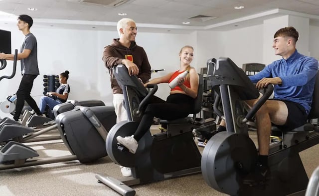 Students exercising on stationary bikes gym area at Piccadilly Point in Manchester Student Accommodation