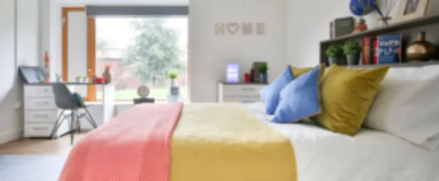 Bed with yellow and pink throws blue pillows bedroom at One & Two Victoria Point in Manchester Student Accommodation