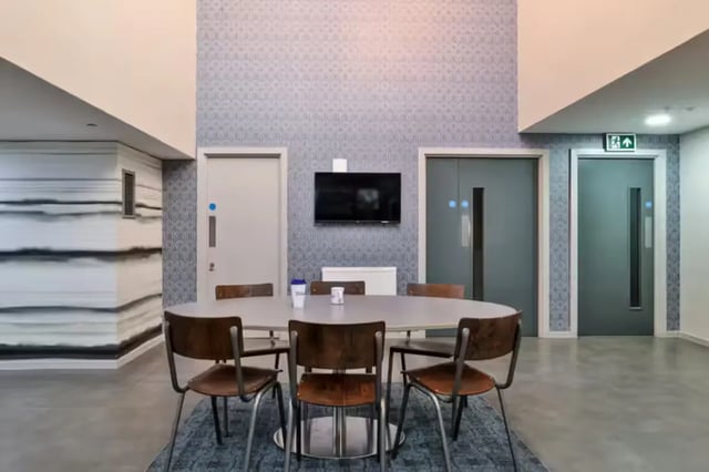 Oval table chairs wall TV lounge area at The Frontage in Nottingham Student Accommodation