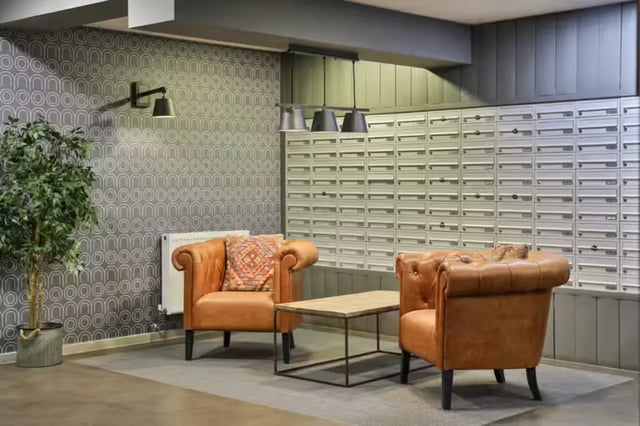 Two armchairs coffee table mailboxes living area at The Frontage in Nottingham Student Accommodation