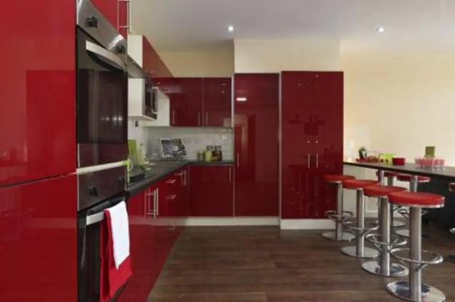 Red kitchen cabinets ovens and bar stools kitchen at Trinity Hall in Chester Student Accommodation