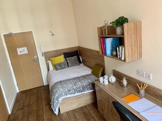 Bed with pillows desk with notebooks and shelving Bedroom at Trinity Hall in Chester Student Accommodation