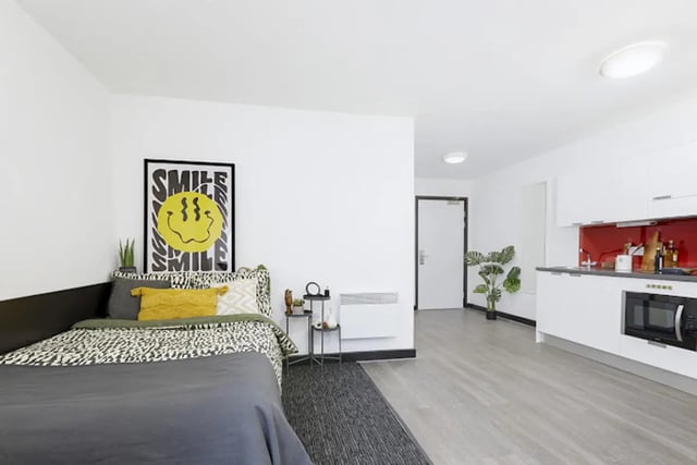 Bed with smiley art kitchen and plants studio apartment at Athena Studios in Birmingham Student Accommodation
