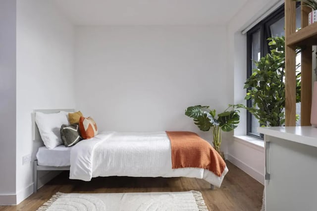 Bed with pillows blanket and plants bedroom at Tramworks in Glasgow Student Accommodation