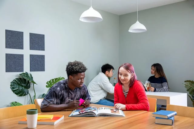 Students studying at table with books plants study area at Tramworks in Glasgow Student Accommodation