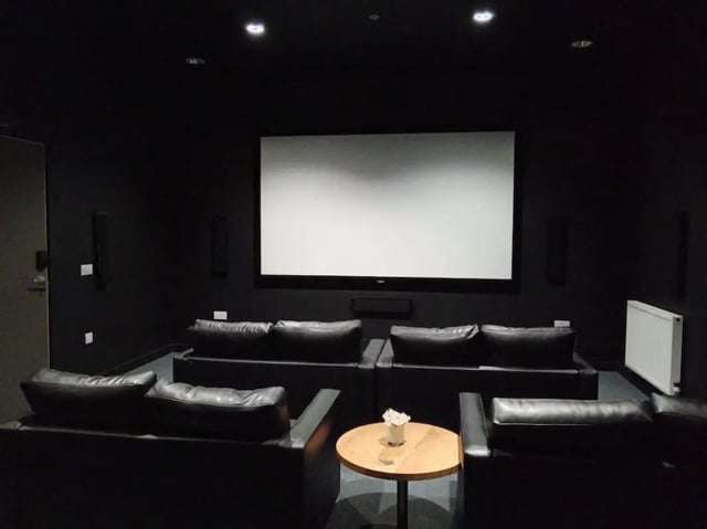 Black couches white screen speakers and table cinema at Bath Street in Glasgow Student Accommodation