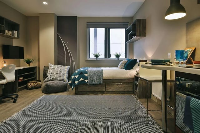 Bed desk chair rug and plants living room at Bath Street in Glasgow Student Accommodation