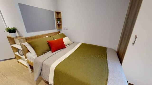 Bed with green bedding shelf and plant bedroom at iQ Elgin Place in Glasgow Student Accommodation