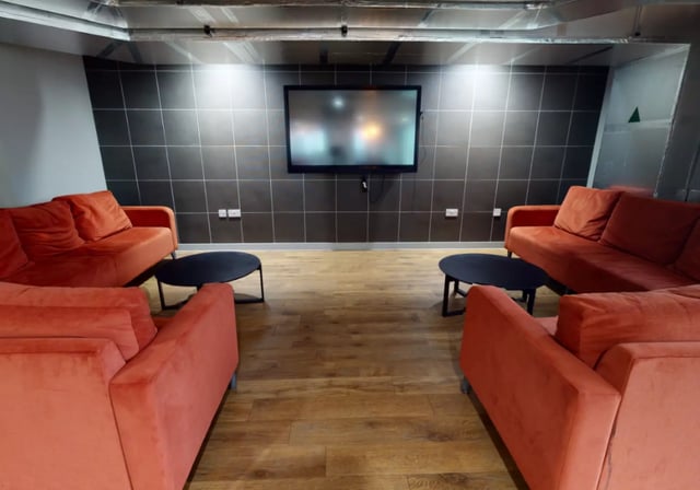 Orange sofas black coffee tables mounted television common area at iQ Elgin Place in Glasgow Student Accommodation