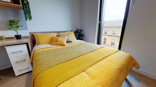 Bed with yellow bedding desk and drawers bedroom at iQ Elgin Place in Glasgow Student Accommodation