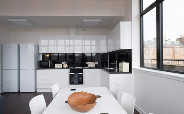Modern kitchen with white cabinets appliances and dining table kitchen at Clifton & Stewart House in Glasgow Student Accommodation