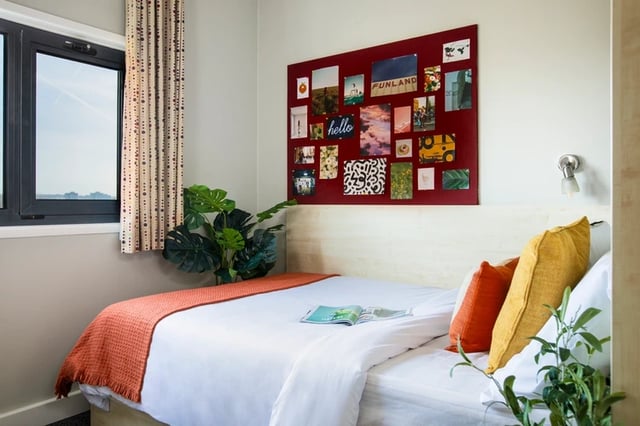Bed with orange throw colorful pillows and photos bedroom at Phoenix Court in Bristol Student Accommodation