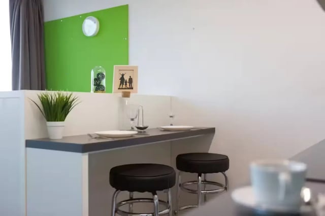 Table with stools plant and clock kitchen area at St Lawrence House in Bristol Student Accommodation