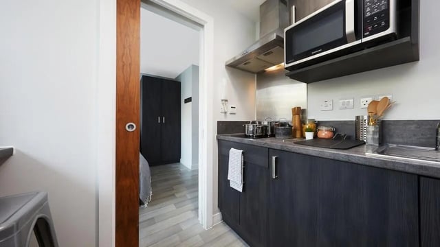 Modern kitchen with microwave and dark cabinets kitchen at Collegiate Tower in Bristol Student Accommodation