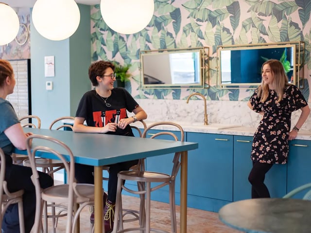 Three students at blue table kitchen area at Yugo Belaton House in Bournemouth Student Accommodation