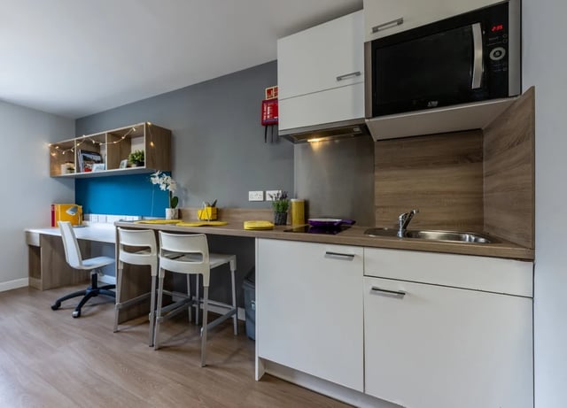 Desk chairs microwave sink and cabinets kitchen area at Haddington Place in Edinburgh Student Accommodation