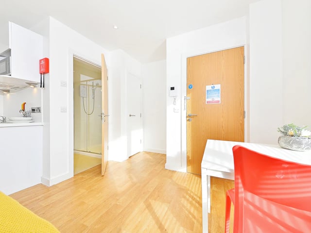 Open shower stall white counter red chair living room at The Pavilion - Leeds in Leeds Student Accommodation