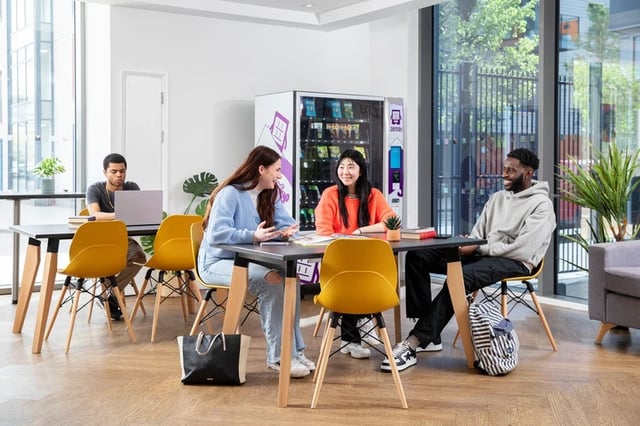 Students sit at tables near vending machine common area at North Lodge in London Student Accommodation