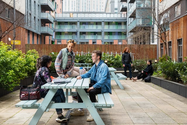 Students chatting at picnic tables outdoors communal area exterior at North Lodge in London Student Accommodation