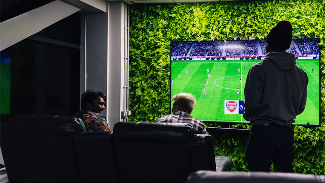 Three men watching football on large screen living room at The Pinnacles in Sheffield Student Accommodation