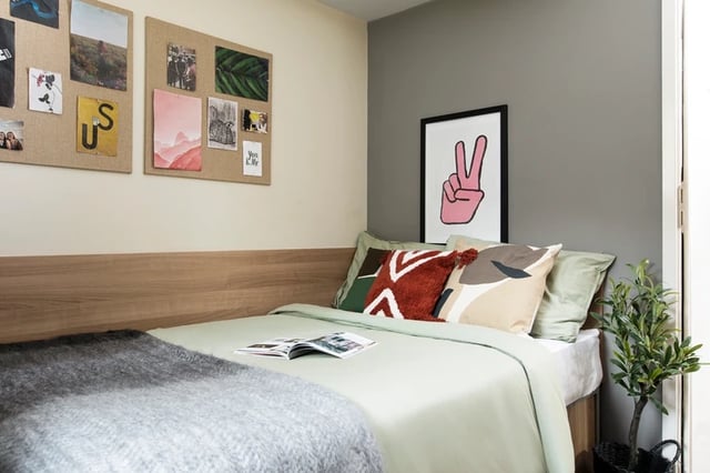 Bed with pillows corkboard and artwork bedroom at Elizabeth Croll House in London Student Accommodation