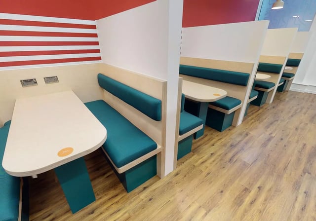 Booths with teal cushions and light wood tables communal area at iQ Bankside in London Student Accommodation