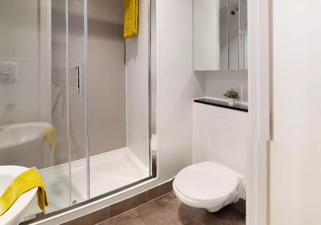 Shower toilet and tub with yellow towels bathroom at iQ Bankside in London Student Accommodation