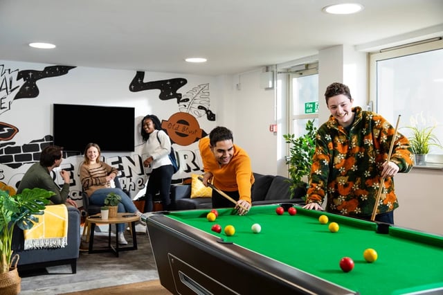 Students playing pool and relaxing living room at East Central House in London Student Accommodation