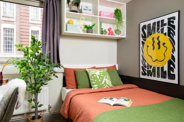Bed with orange bedding and green cushions bedroom at East Central House in London Student Accommodation