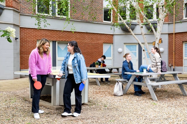 Students playing ping pong and studying outdoors courtyard exterior at East Central House in London Student Accommodation